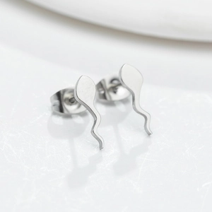 Macro shot of silver tadpole stud earrings with a polished finish on white stone