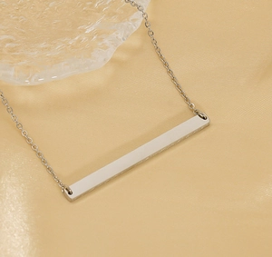 Gros plan d'un collier minimaliste avec pendentif barre en acier inoxydable argenté sur chaîne