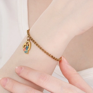 Vue détaillée du bracelet cœur en acier doré avec breloques en émail coloré sur le poignet
