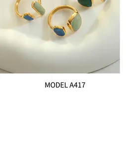 Close-up of vintage gold adjustable rings with blue and green gemstone inlay on a wave stand