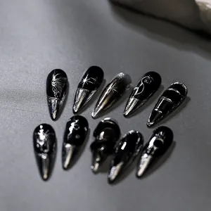 Macro detail of black and silver Y2K press-on nails with celestial star and moon patterns