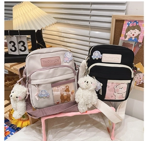 Détail de sacs bandoulière en toile avec écussons d'ours astronaute et breloques peluche