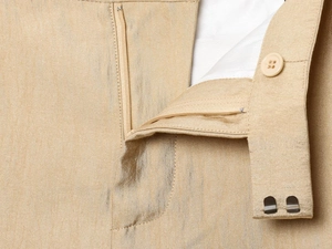 Detail van broek taille met rits, knoop en metalen haken op zijdeachtige textuur