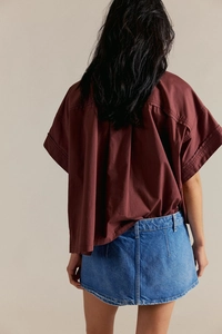 Vista posteriore di una minigonna in denim blu abbinata a una camicia rossa a maniche corte