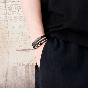Detail of three-piece men's leather bracelets with gold beads and woven textures