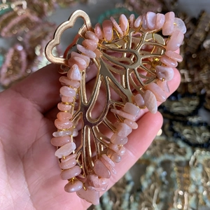 Close-up of golden butterfly hair claw clip with pink orange crystal gravel detailing
