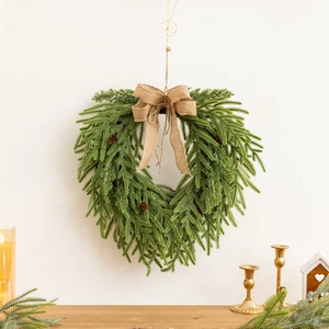 Gros plan d'une couronne de Noël en forme de cœur avec aiguilles de pin et nœud en toile
