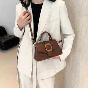 Brown vintage square handbag with gold buckle and adjustable strap on white blazer