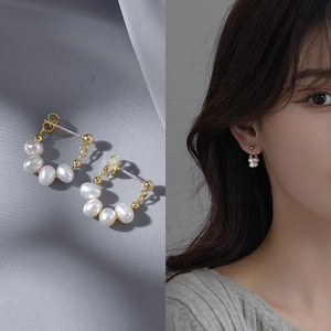Macro shot of natural freshwater pearl earrings with gold metal accents on silk