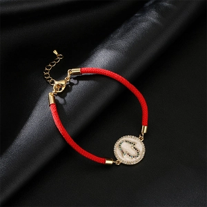 Detail of red braided Hamsa Hand bracelet with gold enamel pendant and sparkling zircons
