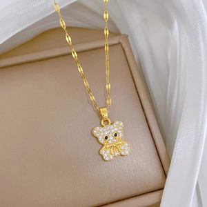 Close-up of gold titanium teddy bear pendant with white zircon inlay on jewelry box