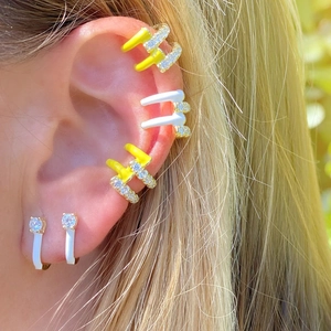 Close-up of yellow and white enamel U-shaped hoop earrings with sparkling zircon stones