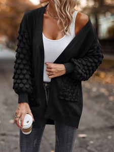 Detailed close-up of black cardigan featuring 3D bubble knit texture on sleeves and pockets