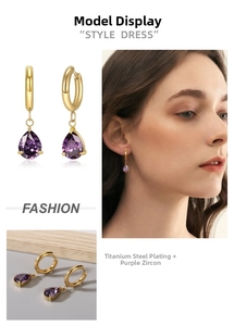 Close-up of titanium steel gold earrings with purple pear-cut zircon pendant drops