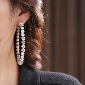 Close-up of luxury silver hoop earrings with clear sparkling zircons on female model
