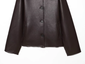 Detail of dark brown leather jacket with button closure and faux shearling lining hem
