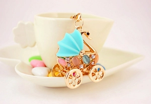Detailed view of baby stroller keychain with colorful cat eye stones and sparkling crystals