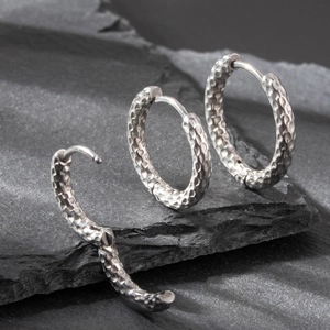 Dettaglio di tre orecchini in argento con finitura martellata su pietra grigio scuro