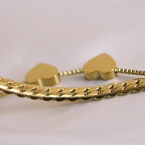 Close-up of dual-layer 18K gold plated stainless steel curb chain with heart charms