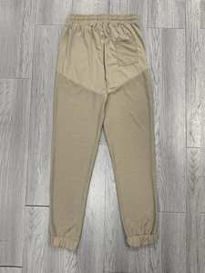 Detail of khaki jogger pants with textured patchwork, drawstring waist and elastic cuffs