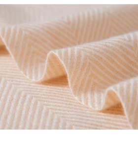 Gros plan sur l'écharpe en maille beige montrant la texture à chevrons et le tissage doux