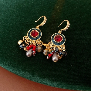Detail von Vintage-Goldohrringen mit roten Steinen und bunten Quasten auf Samt