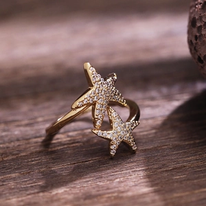 Golden double starfish open ring with sparkling cubic zirconia on dark wood background
