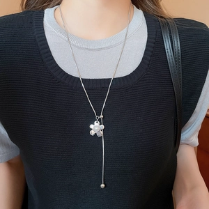 Detail of silver long Y-shaped necklace with wrinkled flower pendant and white pearl