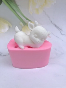 Detail view of pink silicone heart mold with a white sleeping 3D deer figure on marble