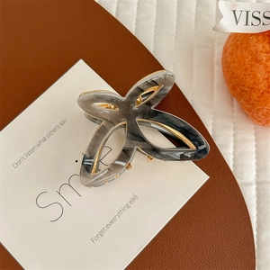 Detail of elegant butterfly hair claw clip with marble texture and gold metal frame