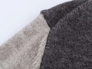 Detailed shot of dark and light gray color-block seams on coarse knit sweater fabric