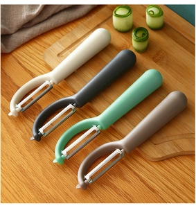 Multi-color kitchen vegetable peelers in white, grey, green and brown on a wooden board