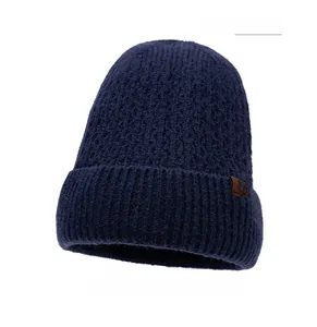 Detailed knit texture and brown leather snowflake tag on navy blue winter beanie