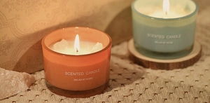 Close-up of lit macaron scented candles with crystals in orange and blue glass jars