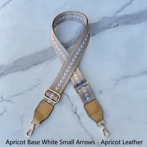Detail of adjustable woven bag strap with white arrow pattern and gold metal lobster clasps