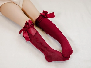 Detailed macro view of burgundy children socks featuring satin bows and wave knit texture
