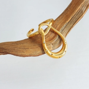 Gold geometric curved ring with micro-set zircons on a rustic wooden branch
