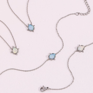 Close-up detail of stainless steel teardrop opal pendant necklaces and chain, vintage style.