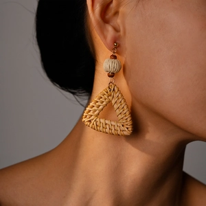 Detailed close-up of a woven rattan triangular earring with a natural bohemian style