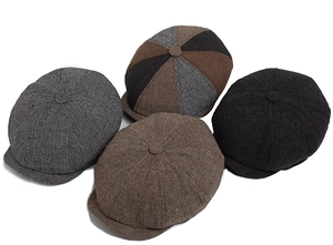 Detailed flat lay of four herringbone newsboy caps in grey, brown, black and patchwork tweed