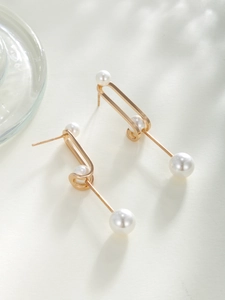Close-up of gold copper earrings with elegant pearls and cubic zirconia stones