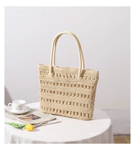 Detail of hollow woven texture on beige straw tote bag with elegant handles for women