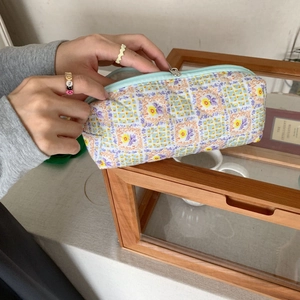 Close-up of a quilted floral pouch being held by hand showing detailed pattern