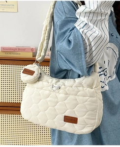 Détail d'un sac à bandoulière matelassé crème avec mini porte-monnaie rond et logo