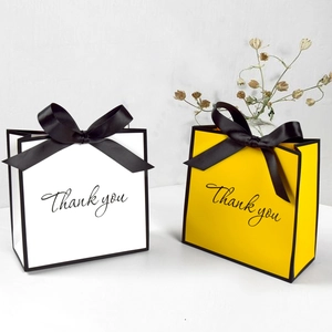 Elegant white and yellow gift bags with black ribbon bows and Thank You text