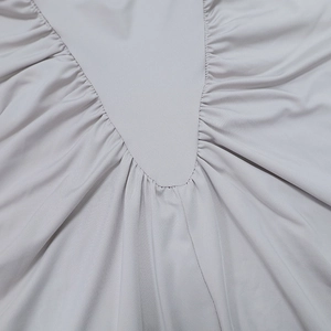 Detailed close-up of gray ruched fabric with professional stitching on high-neck dress