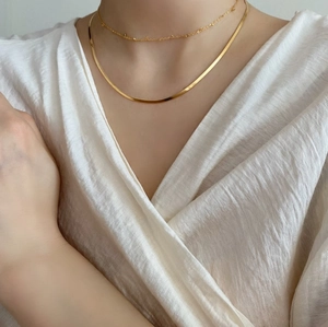 Close-up of a 925 sterling silver gold snake chain layered with a fine bead necklace on model