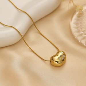 Elegant gold heart pendant necklace with rhinestones and snake chain on silk fabric