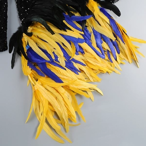 Detail of layered yellow and blue feathers with sparkling black sequins on dress sleeve