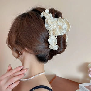 Detail of cream pleated satin hair scrunchie styled on an elegant low bun updo